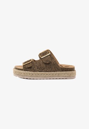 Braune Rutschsandale mit schwarzem Sprenkelmuster, zwei verstellbaren goldenen Schnallen und dicker geflochtener Sohle auf einem weißen Hintergrund.