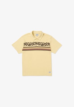 Polo de algodón amarillo claro con un patrón floral en marrón oscuro y franjas granate cerca del pecho. Cuenta con cuello y mangas cortas.