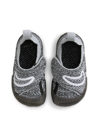 Zapatos de slip-on texturizados en negro y gris con aberturas elásticas, que presentan un diseño de logo blanco y suelas de goma para mayor tracción.