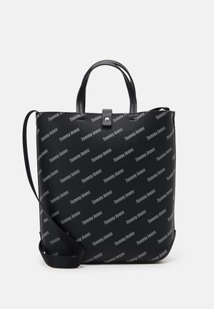 Black rectangular tote bag with two top handles, adjustable shoulder strap, snap closure, and "Tommy Jeans" logo pattern across the surface.