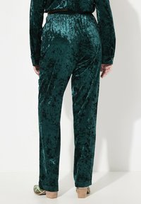 Velvete groene broek met een ontspannen pasvorm, voorzien van een elastische tailleband en een zachte textuur, die tot de enkel reikt met een rechte pijpdesign.