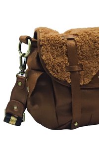 Sac bandoulière marron avec un rabat supérieur duveteux, un corps en cuir, des accessoires en métal et une bandoulière noire avec des accents dorés.
