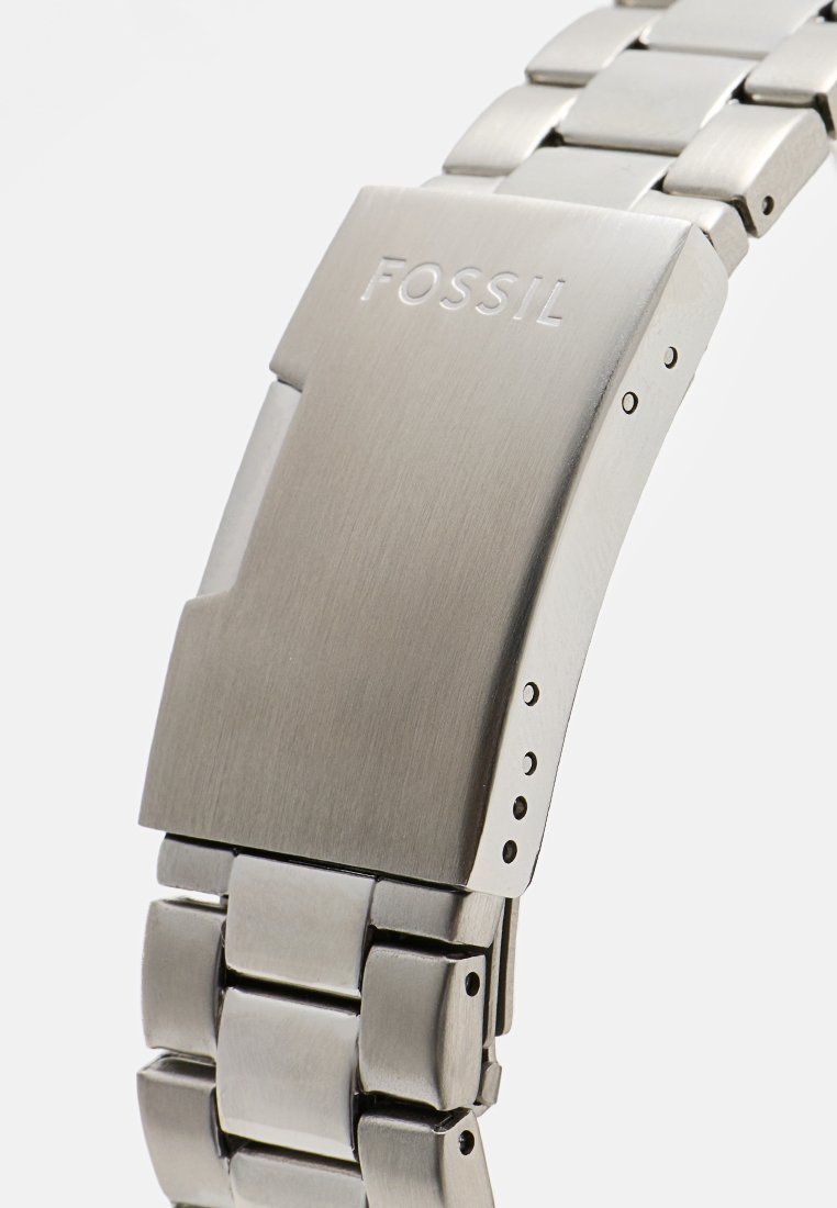 Silberner Edelstahluhren mit gebürsteter Oberfläche, ausgestattet mit einem eleganten, rechteckigen Gehäuse, einem Gliederarmband und dem gravierten "FOSSIL"-Logo.