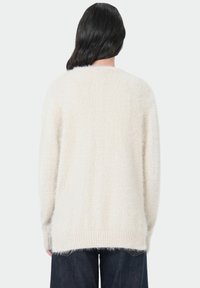 Creme-kleurige gebreide trui met een fluffy textuur, lange mouwen en een geribde onderrand. Heeft een ontspannen fit en een eenvoudig, strak ontwerp.