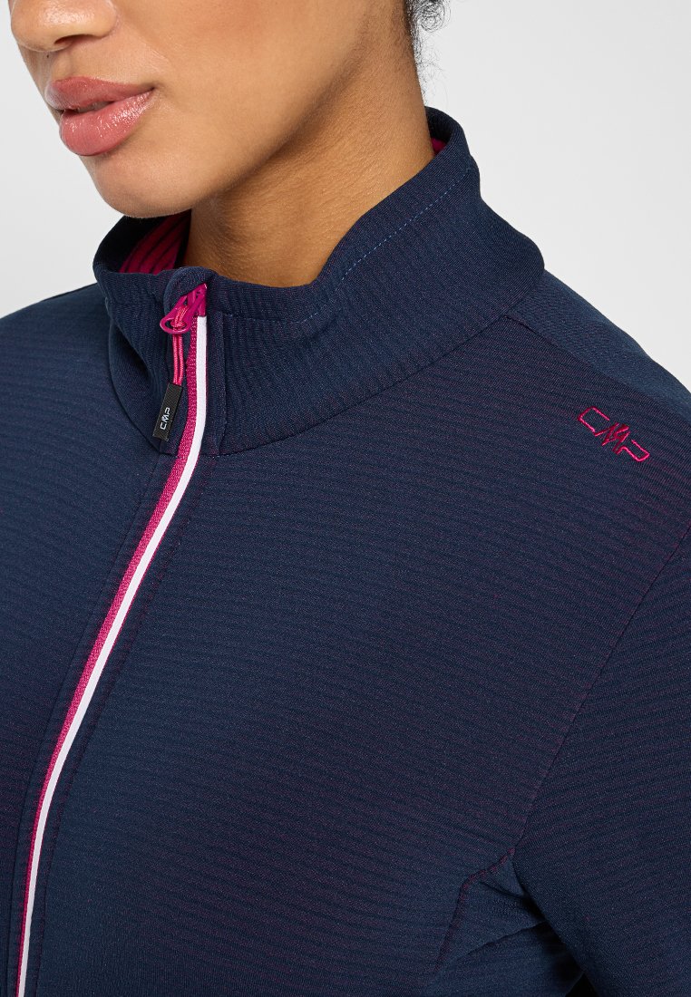 Veste zippée bleu marine avec un col haut, un tissu texturé, des accents de fermeture éclair roses et un logo sur l'épaule.