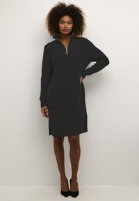 Robe en tricot grise avec une fermeture éclair sur le devant et un col montant. Comprend des manches longues, une silhouette droite et des fentes sur les côtés. Tissu texturé.