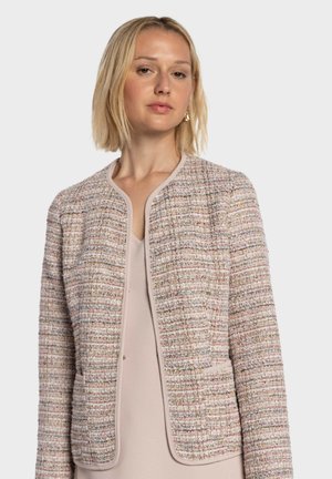 Chaqueta de tweed texturizada en rosa claro con cuello redondeado y apertura frontal. Presenta sutiles motas multicolores y bolsillos a los lados.