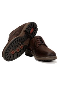 Zapatos de cuero marrón con puntera redondeada, acabado texturizado, diseño con cordones y suela de goma resistente con acentos rojos y dibujo en la suela.