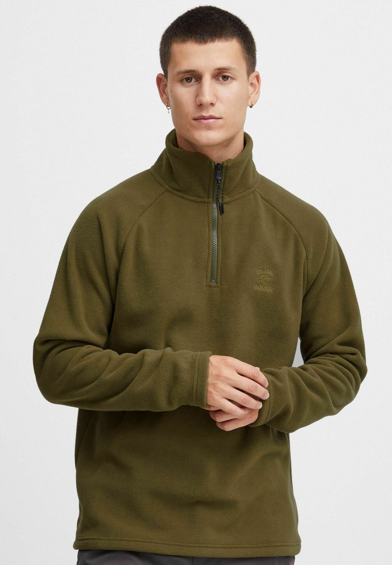 Ciemnozielony polarowy sweter z wysokim kołnierzem, zamek błyskawiczny z przodu do połowy oraz lekką teksturą, z rękawami raglanowymi i detalem logo na piersi.