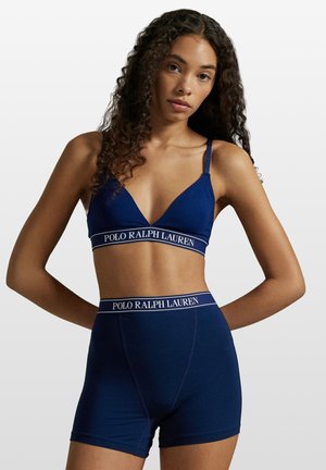 Navy blue bra and shorts set with thin straps, featuring a ribbed texture and logo band in contrasting white. Simple, fitted design.