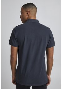 Námořnická polo košile s texturovaným povrchem, krátkými rukávy a klasickým límečkem. Obsahuje rovný lem a decentní švy.