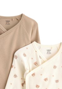 Deux tops enveloppants pour nouveau-nés : l'un en tissu côtelé beige clair, l'autre en crème avec des motifs d'ours brun, tous deux avec un design en V.