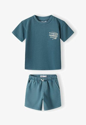 Tirkizna pamučna majica s printom "Los Angeles Tennis Academy 1997" i odgovarajuće kratke hlače s elastičnom gumom u struku i bočnim džepovima.