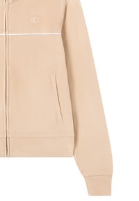 Beżowa bluza z kapturem na zamek, wykonana z miękkiego materiału, z białymi wykończeniami, posiadająca logo na klatce piersiowej oraz kieszeń po lewej stronie.