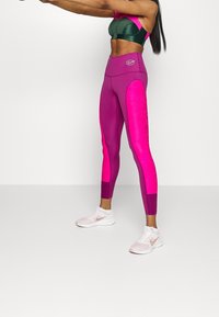 Strakke sportlegging in levendig roze en fuchsia, met textuur aan de zijkanten en een hoge taille. Logo op de tailleband.