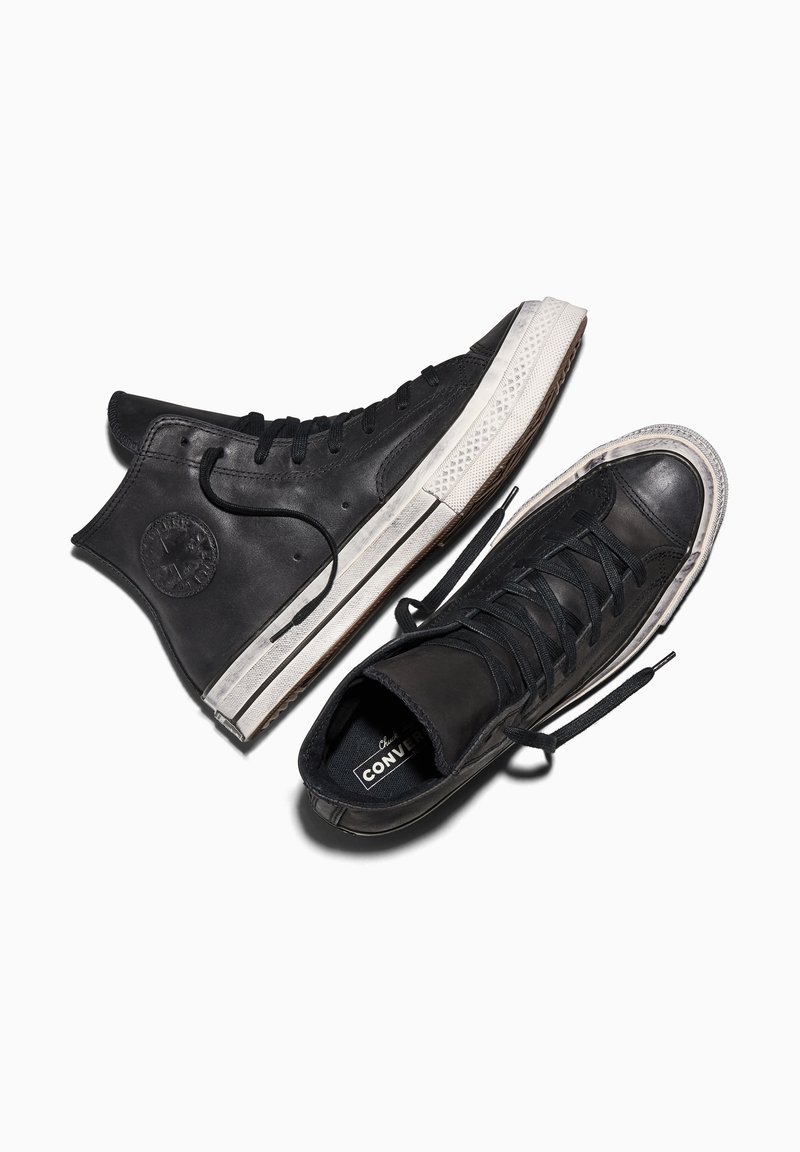Pair of black high-top Converse sneakers with white rubber soles and black laces on a white background.