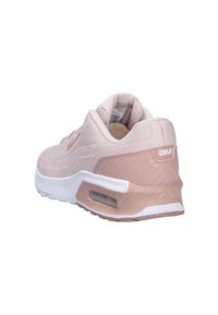 Zapatilla deportiva de color rosa claro y blanco, con parte superior de malla, cuello acolchado, unidad de aire visible en la suela y suela de goma texturizada, vista desde la parte trasera.