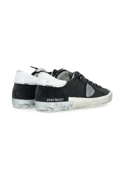 Baskets basses noires et grises avec un dessus en cuir texturé, des accents en daim et une semelle en caoutchouc marbrée blanche avec des éléments de marque.