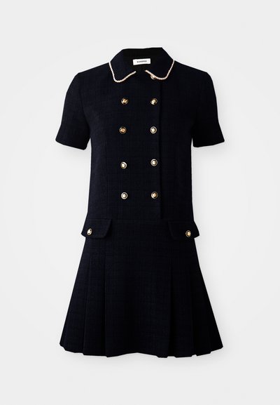 Abito corto navy con maniche corte realizzato in tessuto testurizzato, caratterizzato da dettagli con bottoni dorati, un colletto con bordino simile a perle e una gonna plissettata.