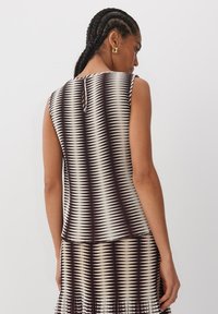 Top senza maniche con un motivo zigzag bianco e nero, caratterizzato da un dettaglio con apertura a chiave sulla schiena, realizzato in tessuto testurizzato.