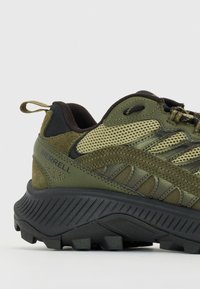 Merrell túracipő olívazöld színben, hálós felsőrésszel, texturált részletekkel és egy strapabíró fekete gumitalppal, mély barázdákkal.