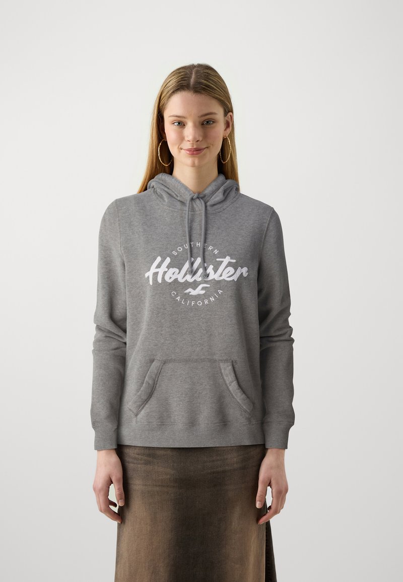 Gray hooded sweatshirt made of soft fabric with a front pocket. Features a white "Hollister" logo and text design on the chest.