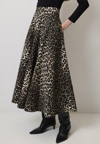 Gonna in stampa leopardata nera e beige, con un design svasato, tasche e vita alta. Indossata con stivali neri a punta.