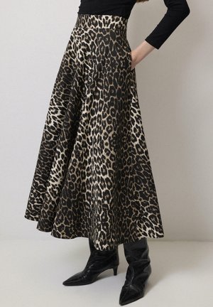 Leopard print skirt in black and beige, featuring a flared design, pockets, and a high waist. Worn with pointed black boots.