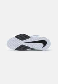 Sport shoe outsole featuring a textured white rubber surface with black accents, a curved black logo, and a geometric tread pattern.