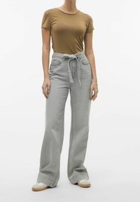 Jeans grises de tiro alto y pierna ancha con cinturón de lazo, combinados con una camiseta marrón ajustada. Tejido de algodón suave con un diseño minimalista.