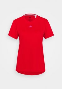 Camiseta deportiva roja con cuello redondo, mangas cortas y un ligero dobladillo trasero. Presenta el logo de Adidas en un tono más claro en el pecho.