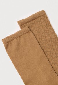 Καφέ κάλτσες με λείο υφή στη μία πλευρά και σχεδιασμό με σχέδιο στην άλλη. Και οι δύο έχουν ριμπ μανσέτα στην κορυφή.