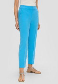 Lichtblauwe op maat gemaakte broeken met een slim fit, voorzien van voorzakken en een soepele textuur. Gecombineerd met zilveren sandaaltjes met bandjes.