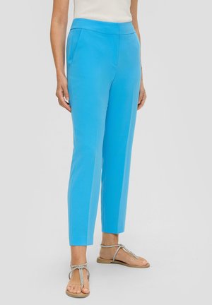 Pantalons taillés bleu clair avec une coupe ajustée, dotés de poches avant et d'une texture lisse. Complétés par des sandales argentées à brides.