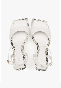 Witte sandalen met vierkante tenen, voorzien van een gestructureerde slangprintzool en slanke enkelbandjes met een gouden gespdetail.