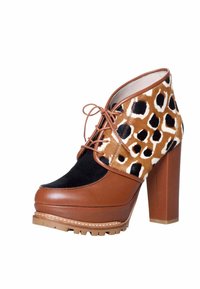 Botas de tobillo de cuero marrón con parte superior de estampado de leopardo, detalles en ante negro, un tacón grueso y una suela de plataforma robusta con dibujo.