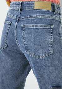 Vaqueros de denim en azul claro con un acabado texturizado, con una cintura alta, dos bolsillos traseros y una pequeña etiqueta en la parte trasera.