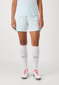 Heledad sinine ja valge Nike jalgpallilühikesed püksid, millel on võrkmaterjal. Koos valgete põlvesokkide ja punase aktsendiga valgete jalgpallijääkidega.