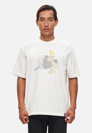 Camiseta de algodón blanca con un gráfico de un personaje con cabello rubio, usando gafas de sol, sobre un fondo azul claro.