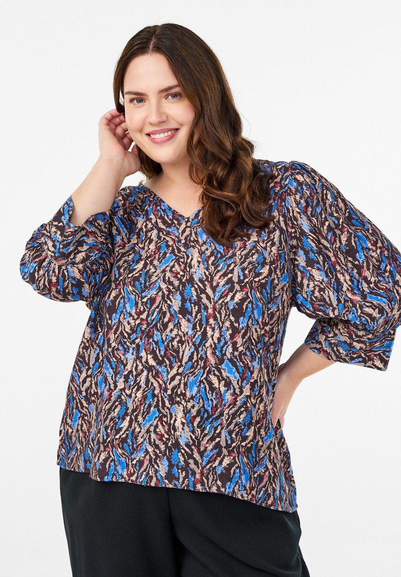 Løs pasform bluse med et levende abstrakt mønster i blå, beige og rød på en mørk baggrund, med puffede ærmer og V-udskæring.