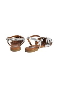 Silberne metallische Sandalen mit einem geflochtenen Vorderdesign, brauner Lederinnensohle und verstellbarem Schnallenriemen. Flache Sohle mit genähten Details.