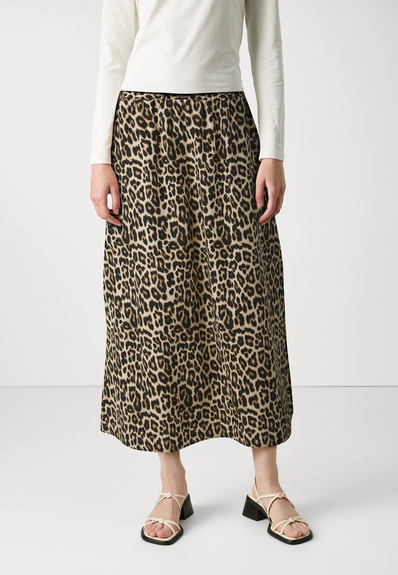 Jupe midi à imprimé léopard avec une taille élastique. Fabriquée en tissu léger. Associée à des sandales crème à brides et un haut blanc ajusté.