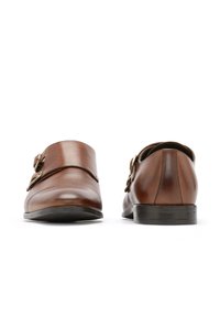 Pantofi din piele maro cu accente cu două catarame, vârf rotund, textură netedă și toc mic negru; priviți din spate.