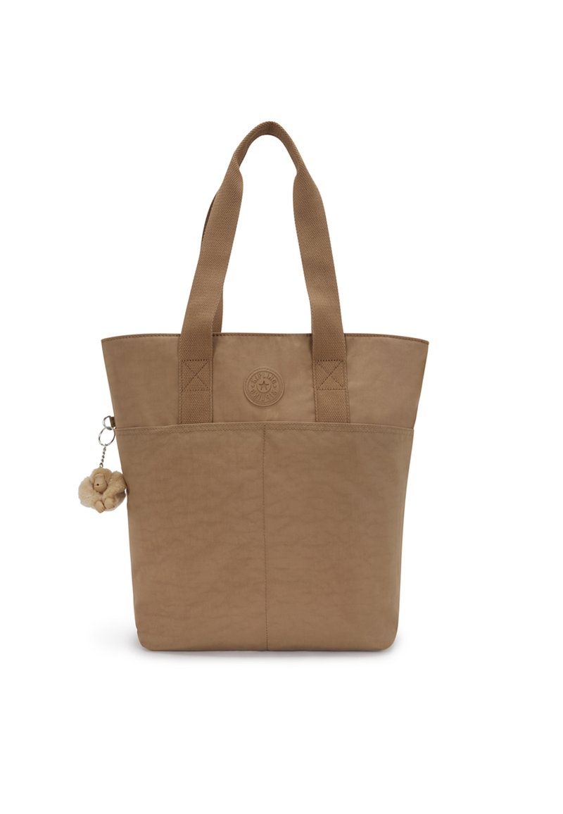 Beige tote bag with two sturdy handles, textured finish, front logo detail, and a decorative charm attached to the side.