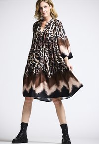 Leopardenmuster Kleid aus leichtem Stoff, mit einem mehrlagigen Design und V-Ausschnitt, mit braunem und schwarzem Ombre am Saum. Getragen mit schwarzen Stiefeln.