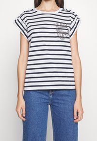 Camiseta de manga corta a rayas en gris y navy, con un bolsillo decorado con un diseño de calavera de lentejuelas, escote redondo y corte relajado.
