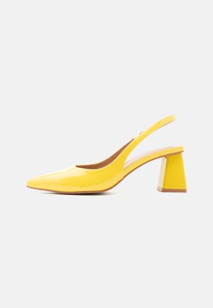 Zapato slingback de charol amarillo con punta puntiaguda y tacón de bloque sobre fondo blanco.