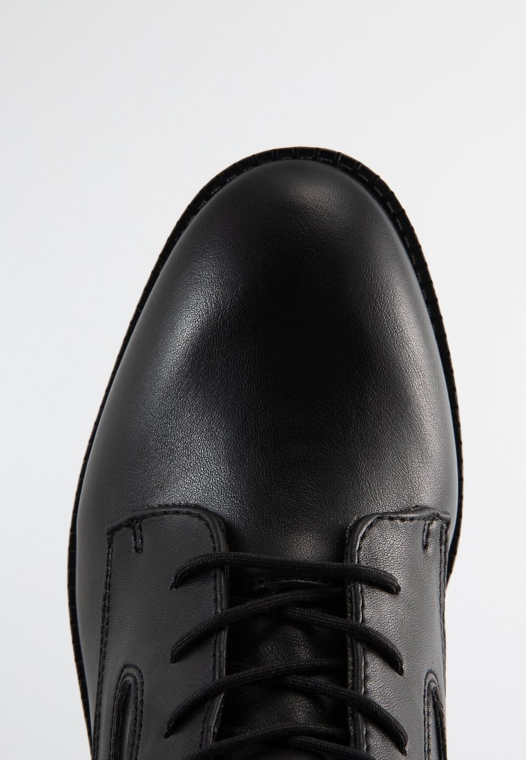 Czarna skórzana półbut z zaokrąglonym noskiem, sznurowanym wzorem i teksturowanym wierzchem. Posiada gładką powierzchnię i wzmocnione detale szwów.