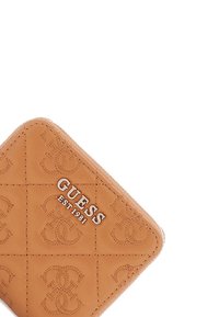 Portafoglio in pelle beige con motivi logo in rilievo, presenta hardware argentato con il testo "GUESS EST 1981" e una superficie liscia.