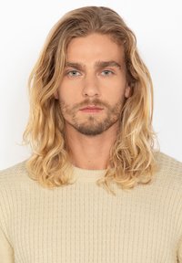 Jasnobeżowy sweter z dzianiny z teksturowanym wzorem i okrągłym dekoltem, noszony przez osobę z długimi, falującymi blond włosami i jasną brodą.